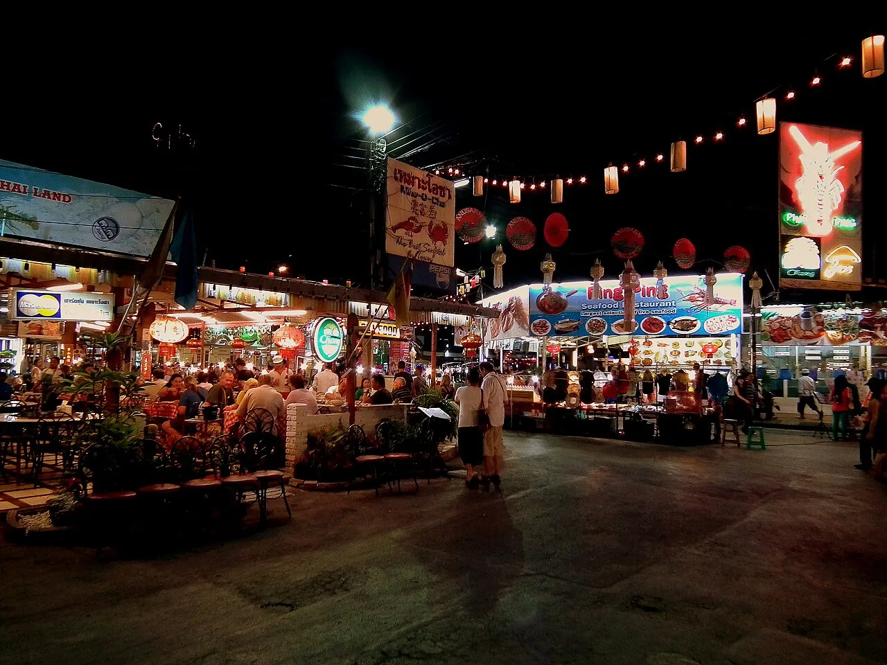 Shoppers browsing stalls at Chiang Mai's Night Bazaar on Chang Klan Road after dark.
