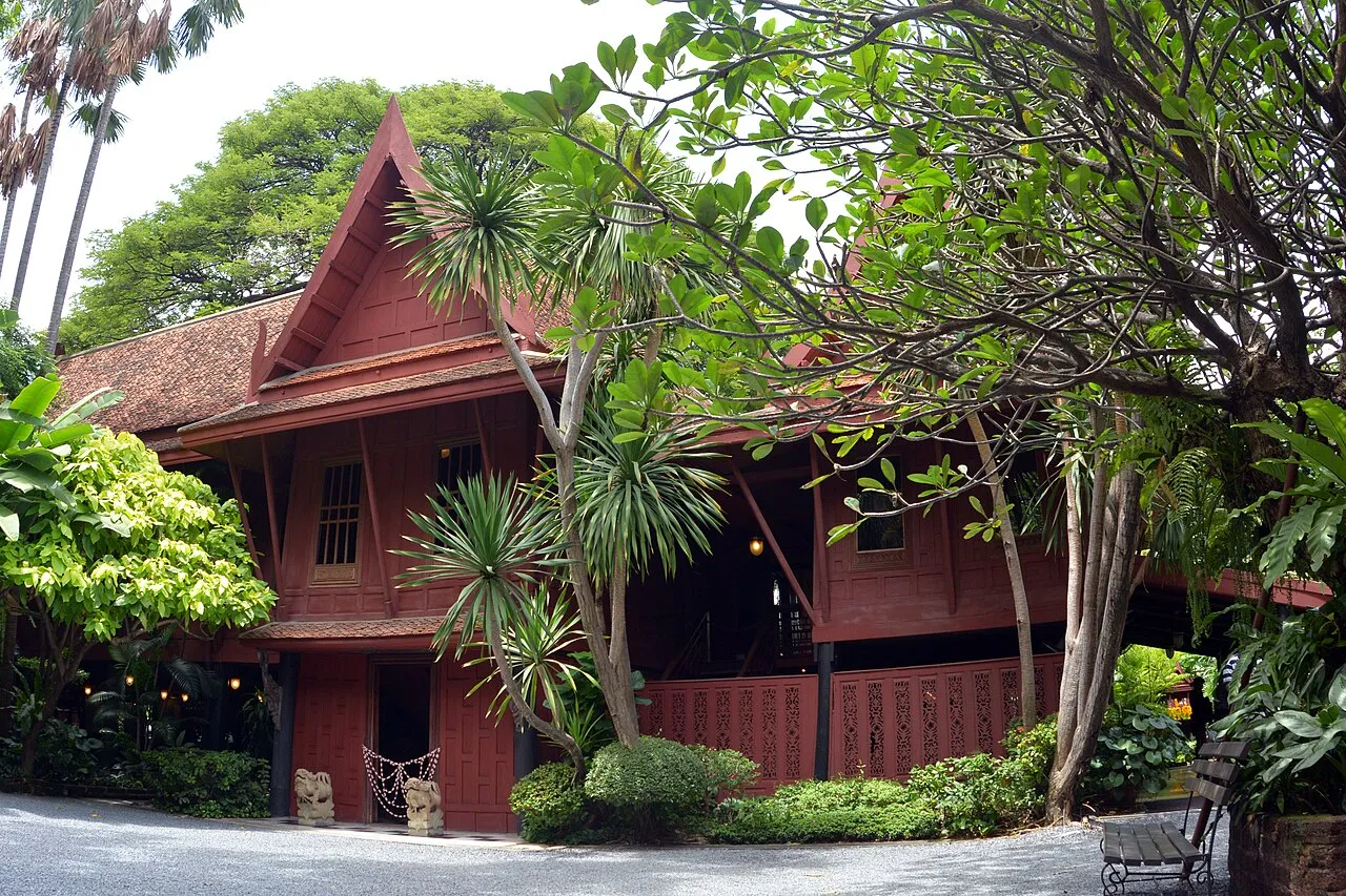 The traditional teak main house of the Jim Thompson House museum, raised on stilts amid tropical garden greenery in Bangkok