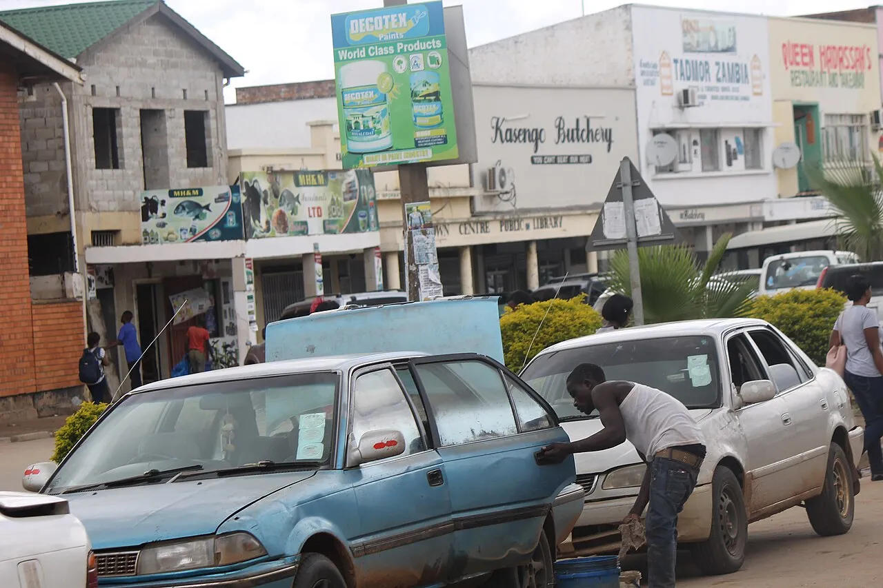 A busy taxi rank in Kabwe, Zambia, with minibuses and passengers at a local transport hub.