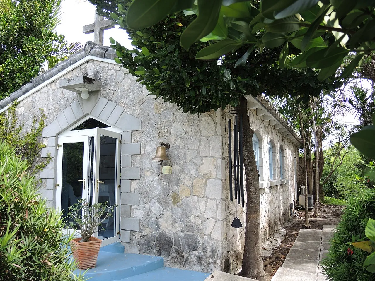 A small white chapel with a bell tower standing among tropical trees and greenery at the Garden of the Groves