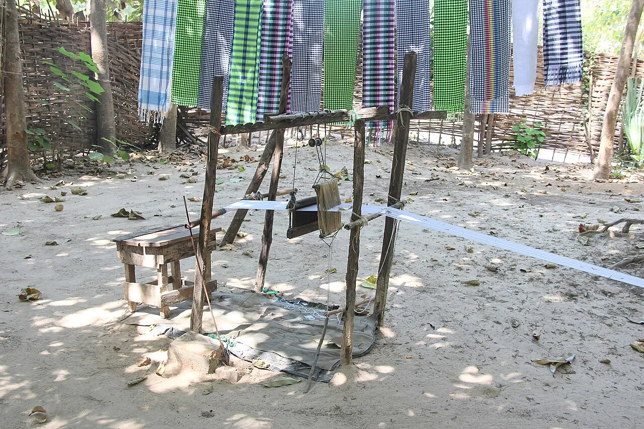 A man working a traditional narrow-strip weaving loom in the Gambia.