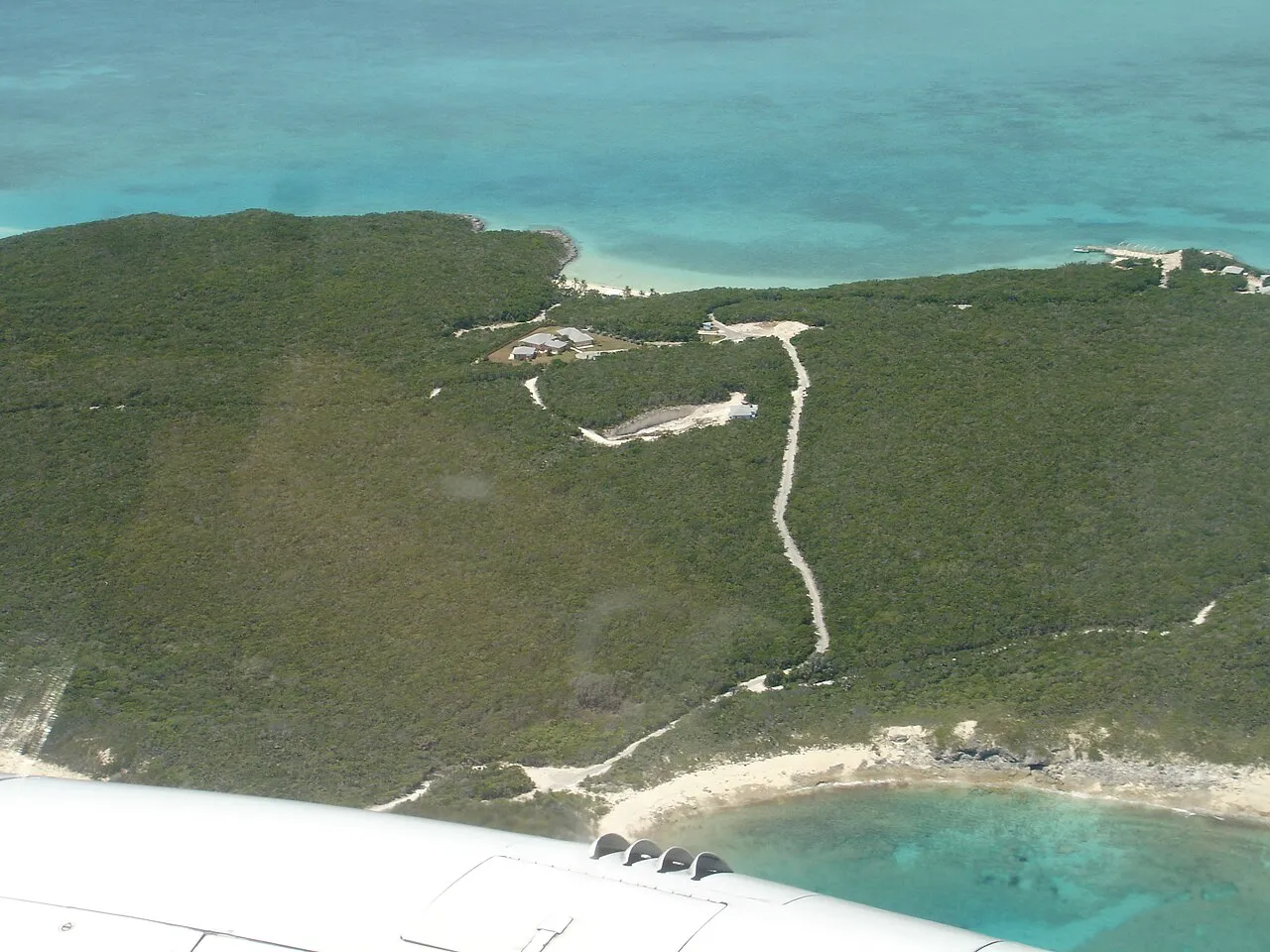 An aerial view of Williams Cay, a small low-lying island in the Great Exuma chain of the Bahamas, surrounded by shallow turquoise water.