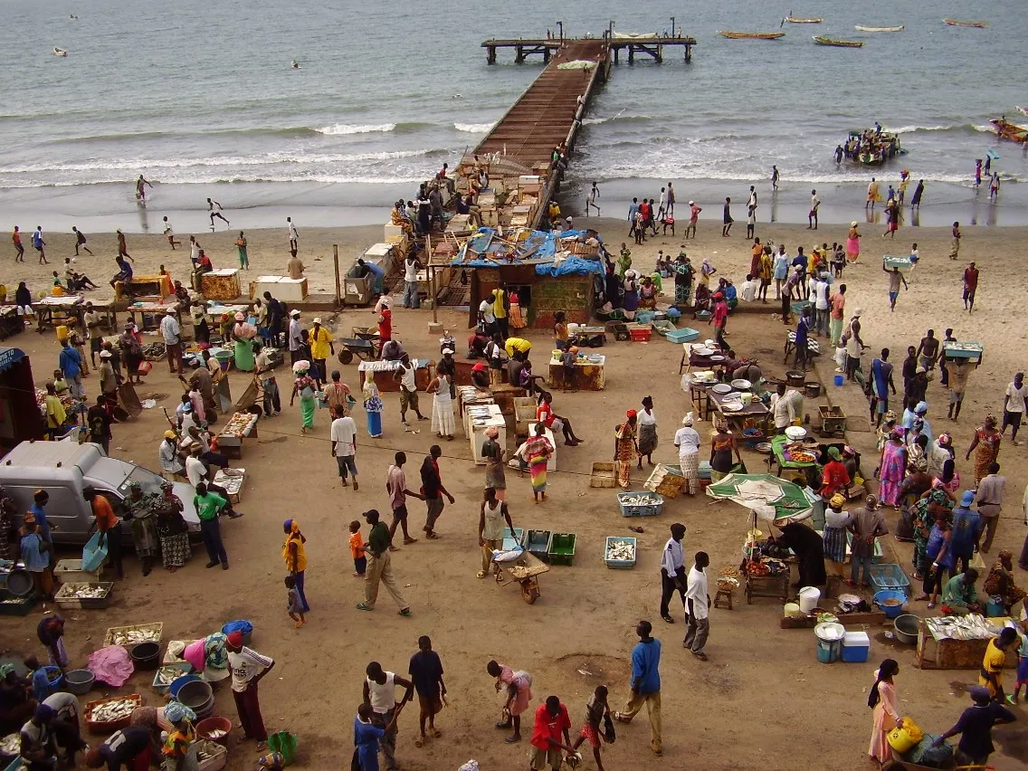 Fishing pirogues and traders at the fish market on Bakau's beach, Gambia.