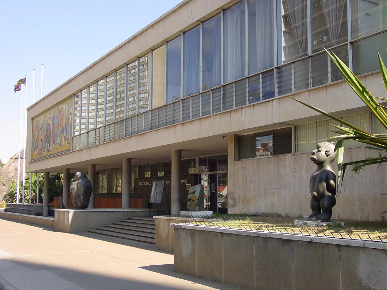 The National Gallery of Zimbabwe building in Harare, with the national flag and outdoor statuary in front.