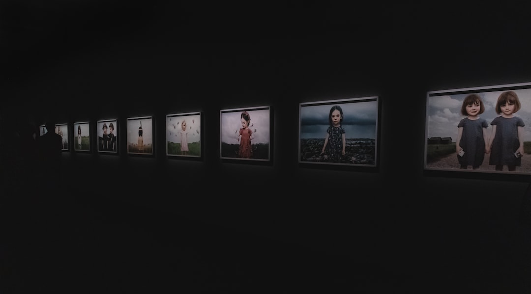 A row of lit, framed photographs of children in a darkened gallery at Fotografiska, Stockholm