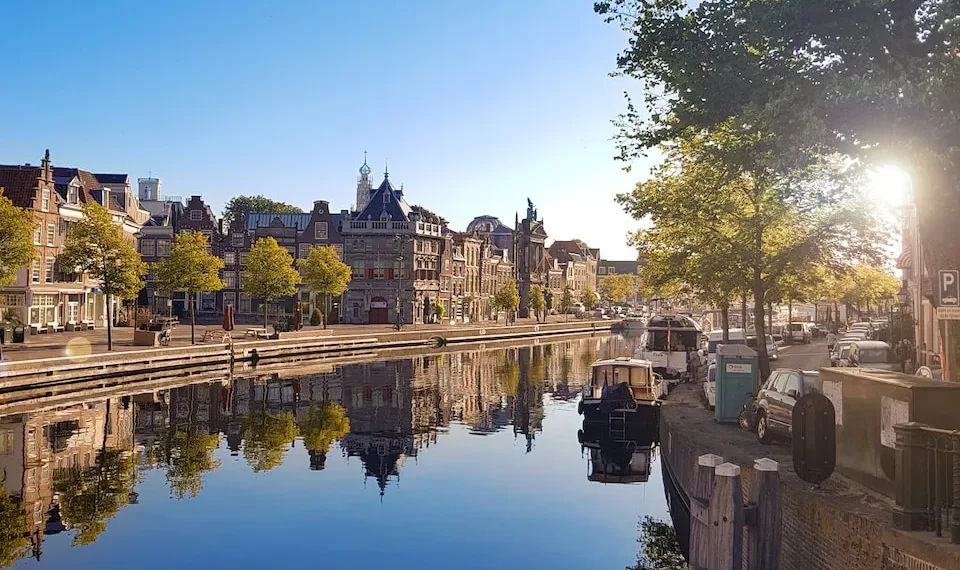 gray concrete buildings near sea viewing lake under blue and white skies